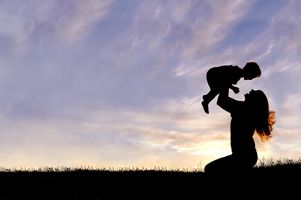 Silhouette of Happy Mother Playing Outside with Baby