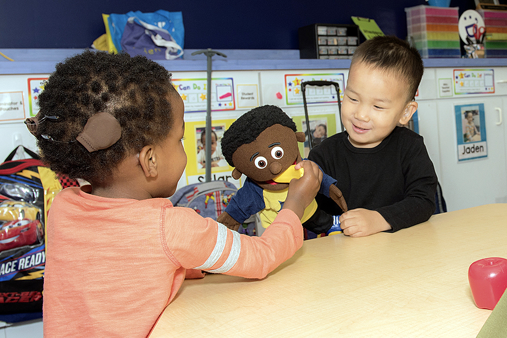 Interactive play between preschool students encourages language exposure.