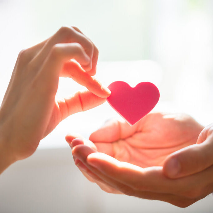 Woman Giving Heart On Man's Hand